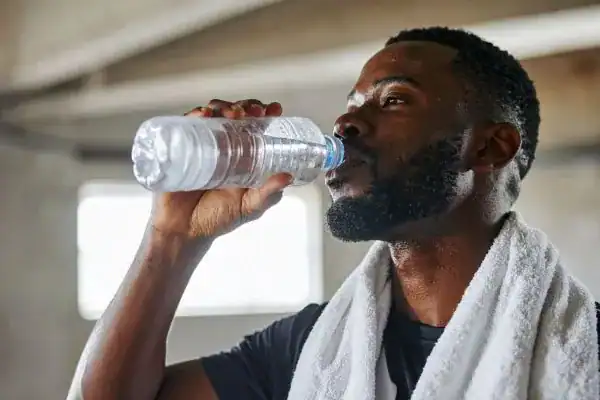 Image of man drinking water to improve hydration Farnham after work out.